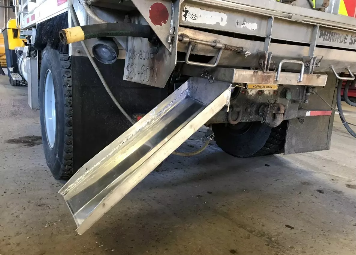 An image of a metal chute mounted to rear of PennDOT dump truck.